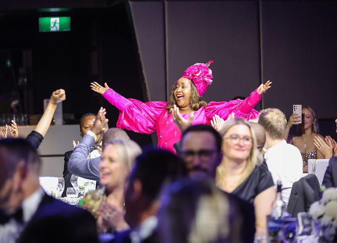 A person standing in the audience with their hands in the air 