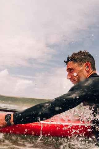 A man with a paddle board in the water wearing an Apple Watch Series 10