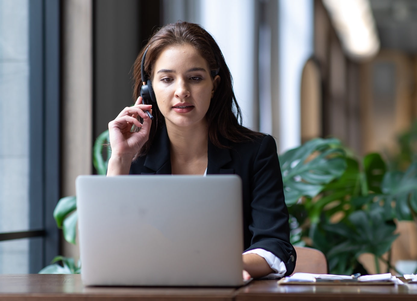 A person wearing a headset using a laptop in an office.