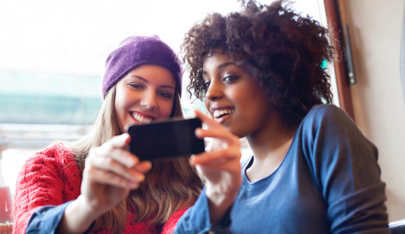 Two adults smiling at a mobile screen.