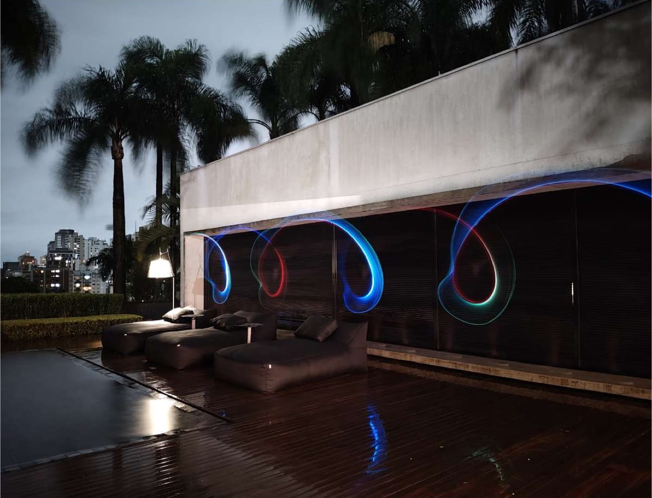 A photo of coloured light trails that spiral over an outdoor setting at night.