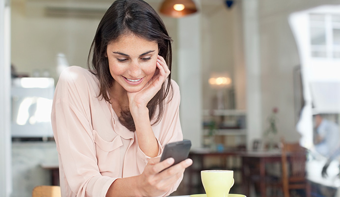 Two people in a cafe looking at their phone