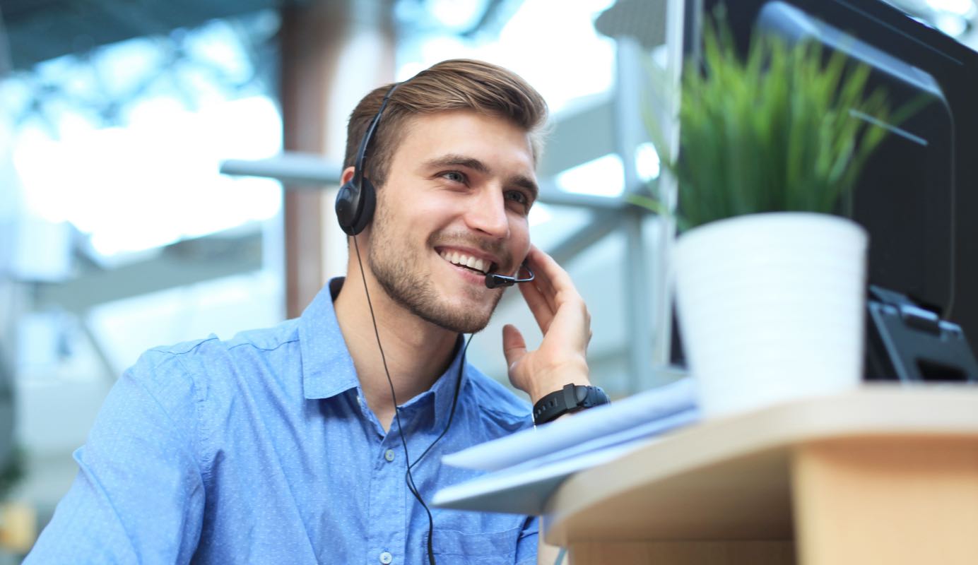 Male call centre operator wearing a headset talking to a client on the phone.